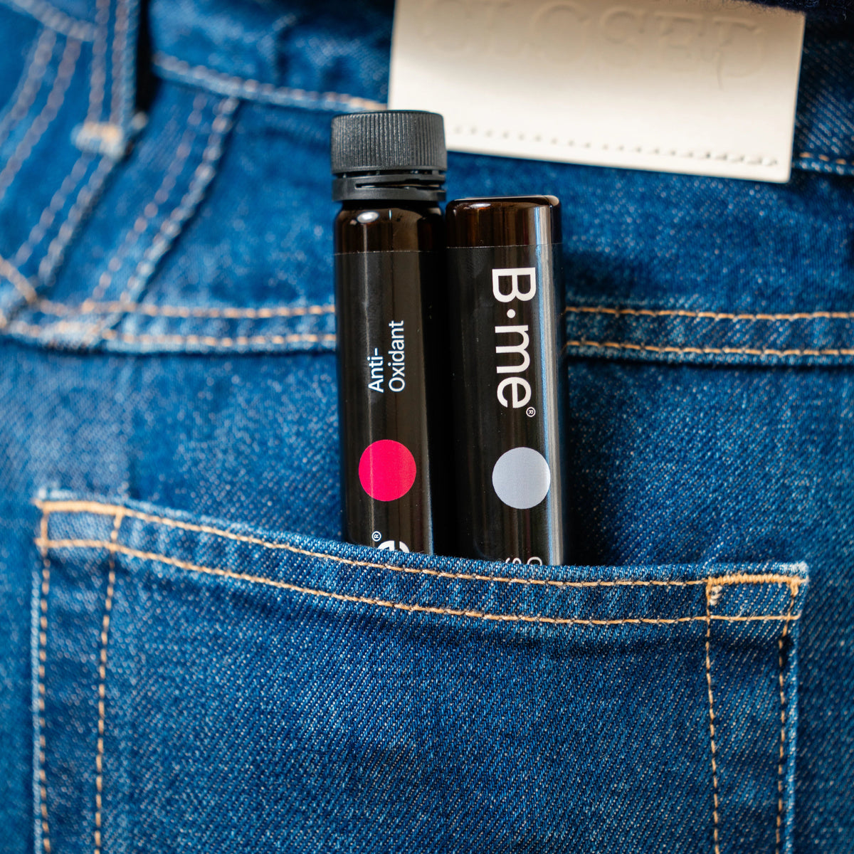 B.me Antioxidant and Clear Skin supplement shots tucked into a jeans pocket