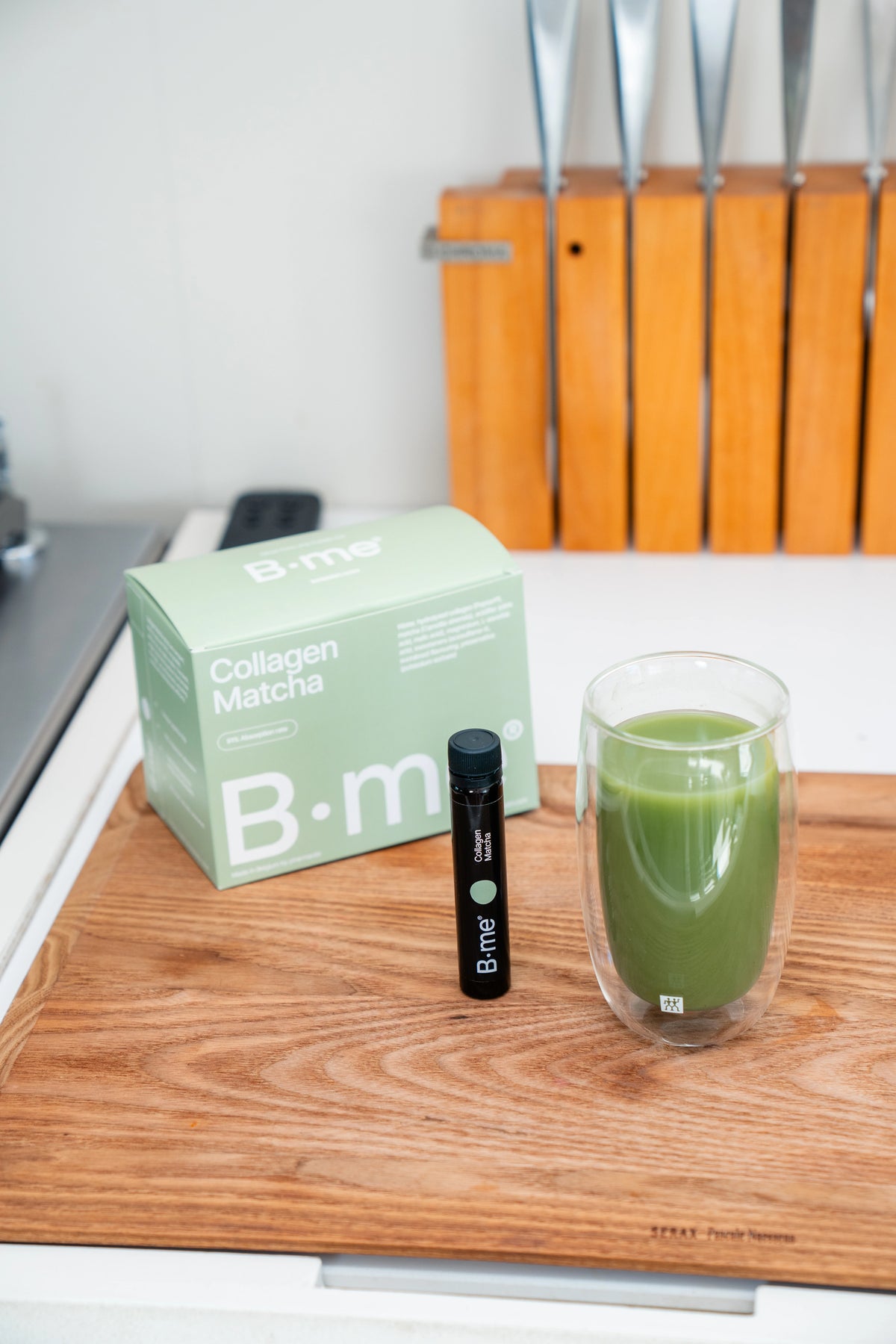 B.me Collagen Matcha shot placed next to a ceremonial matcha drink in a kitchen setting