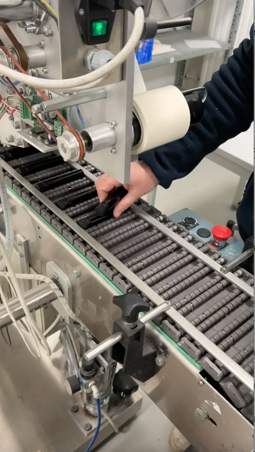 en medewerker plaatst Collagen Advance+ flacons op de lopende band voor etikettering