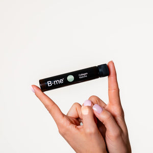 One hand with pink gel nails holding B.me collagen matcha supplement sho