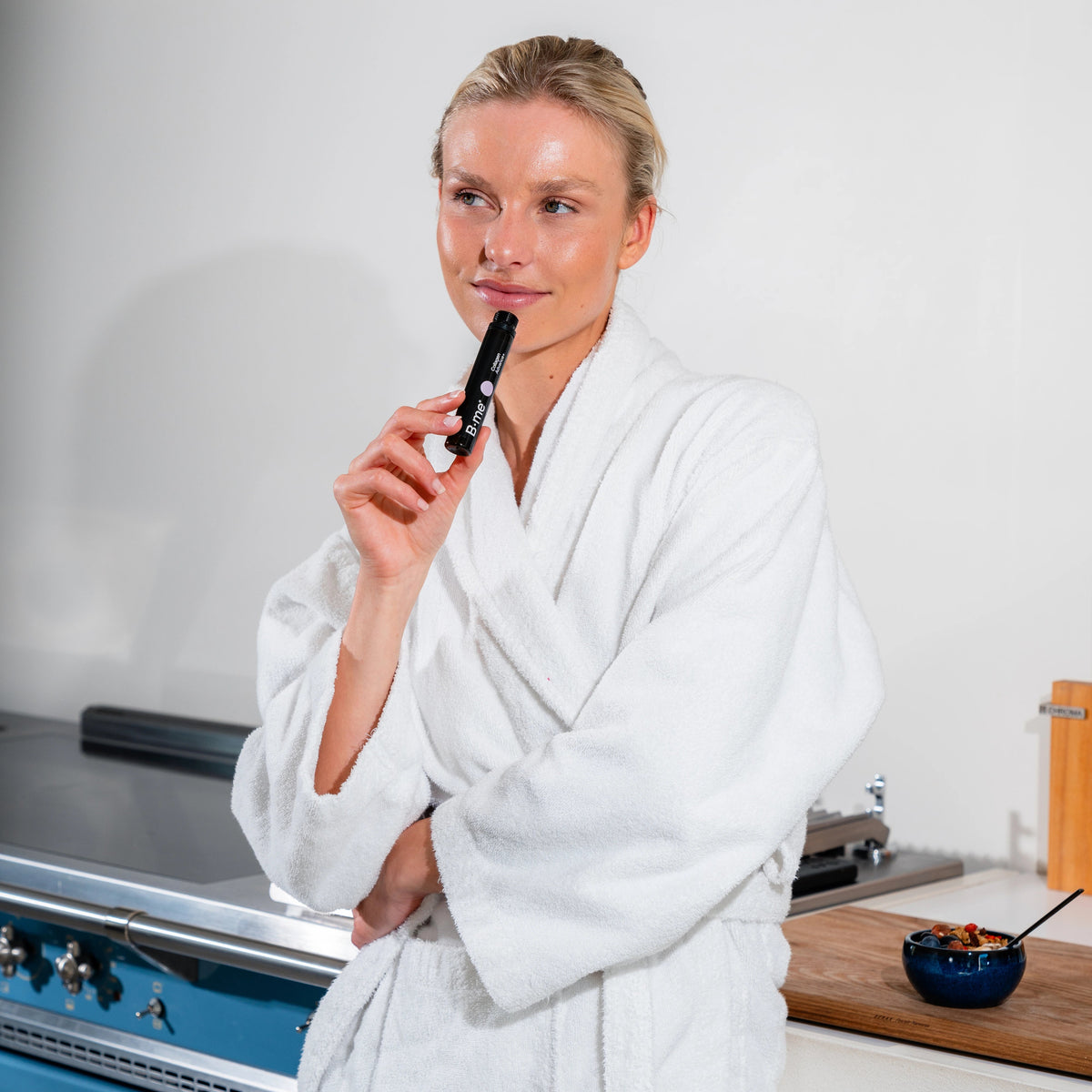 Iris Thooft in bathrobe with natural glow, enjoying breakfast in the kitchen with B.me Collagen Advance+ shot