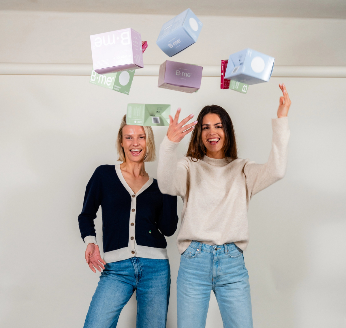 Larissa de Castro and Iris Thooft playfully throwing B.me supplement boxes in the air