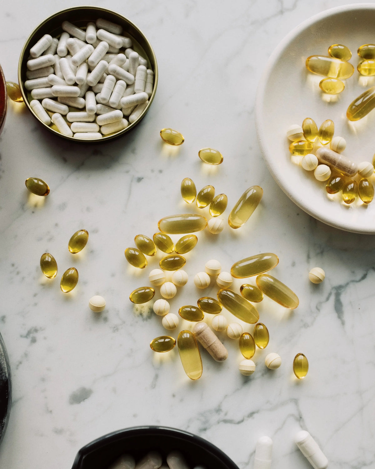 A flatlay of traditional supplements including capsules, tablets, and softgels — highlighting the clutter and complexity of conventional supplement routines compared to B.me's convenient liquid alternatives.