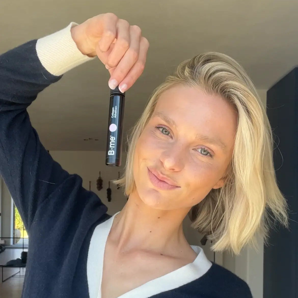 Iris holding the B.me Collagen Advance+ shot, promoting skin hydration, elasticity, and glow with scientifically backed ingredients like collagen peptides and hyaluronic acid.