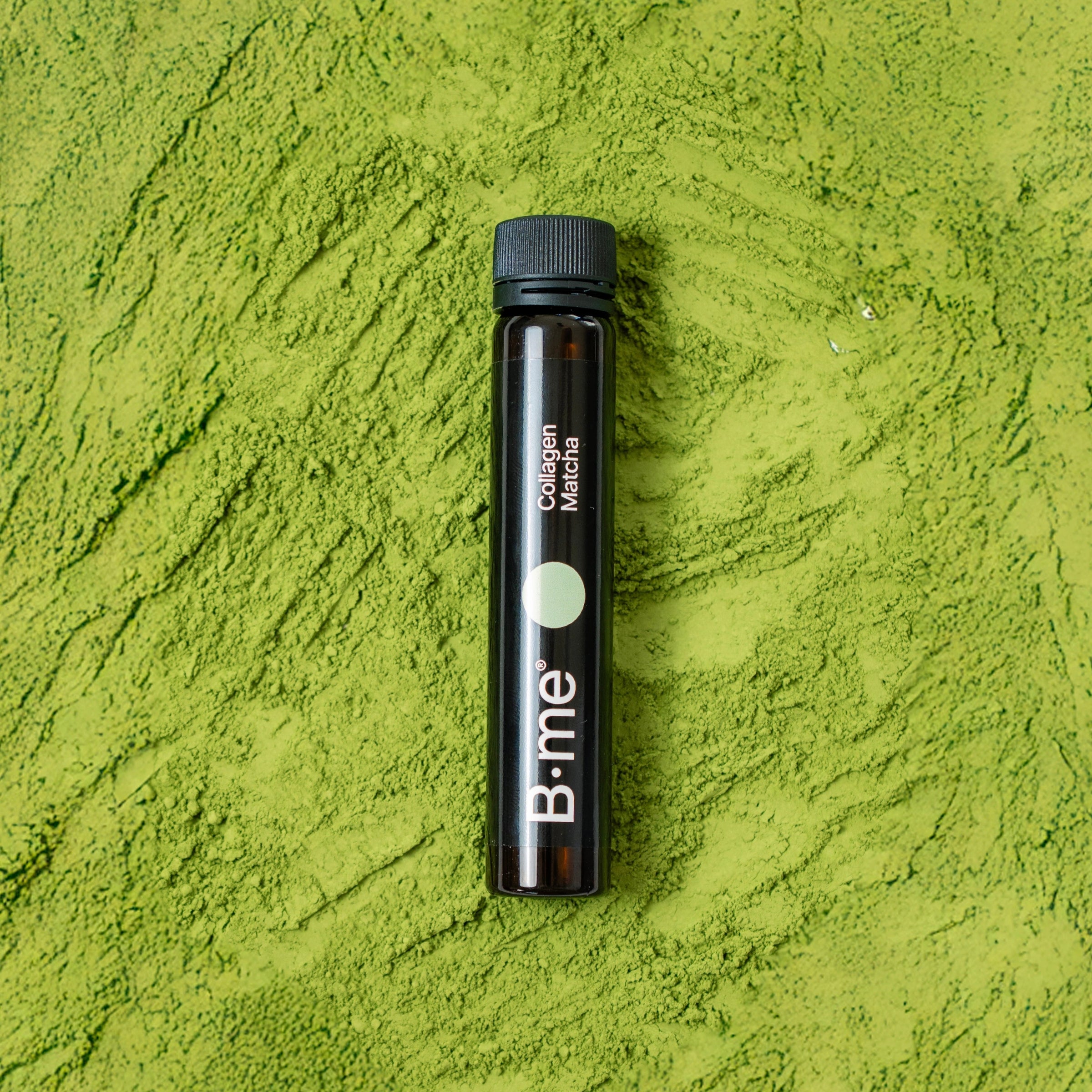 B.me Collagen Matcha shot laying in a bed of vibrant green matcha powder
