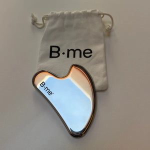 B.me roestvrij stalen gua sha massagetool met wit katoenen bewaarzakje met B·me logo