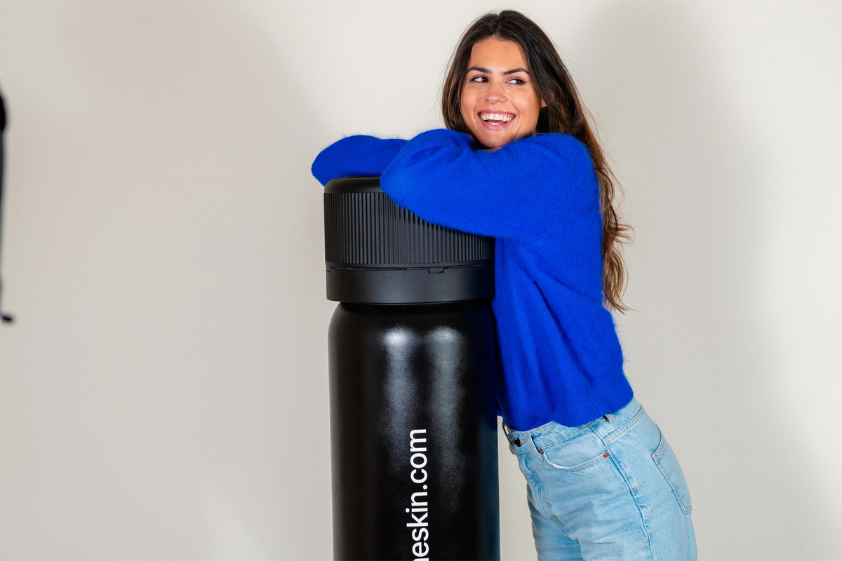 Larissa de Castro smiling in blue sweater while leaning on large 3D-printed B.me ampoule