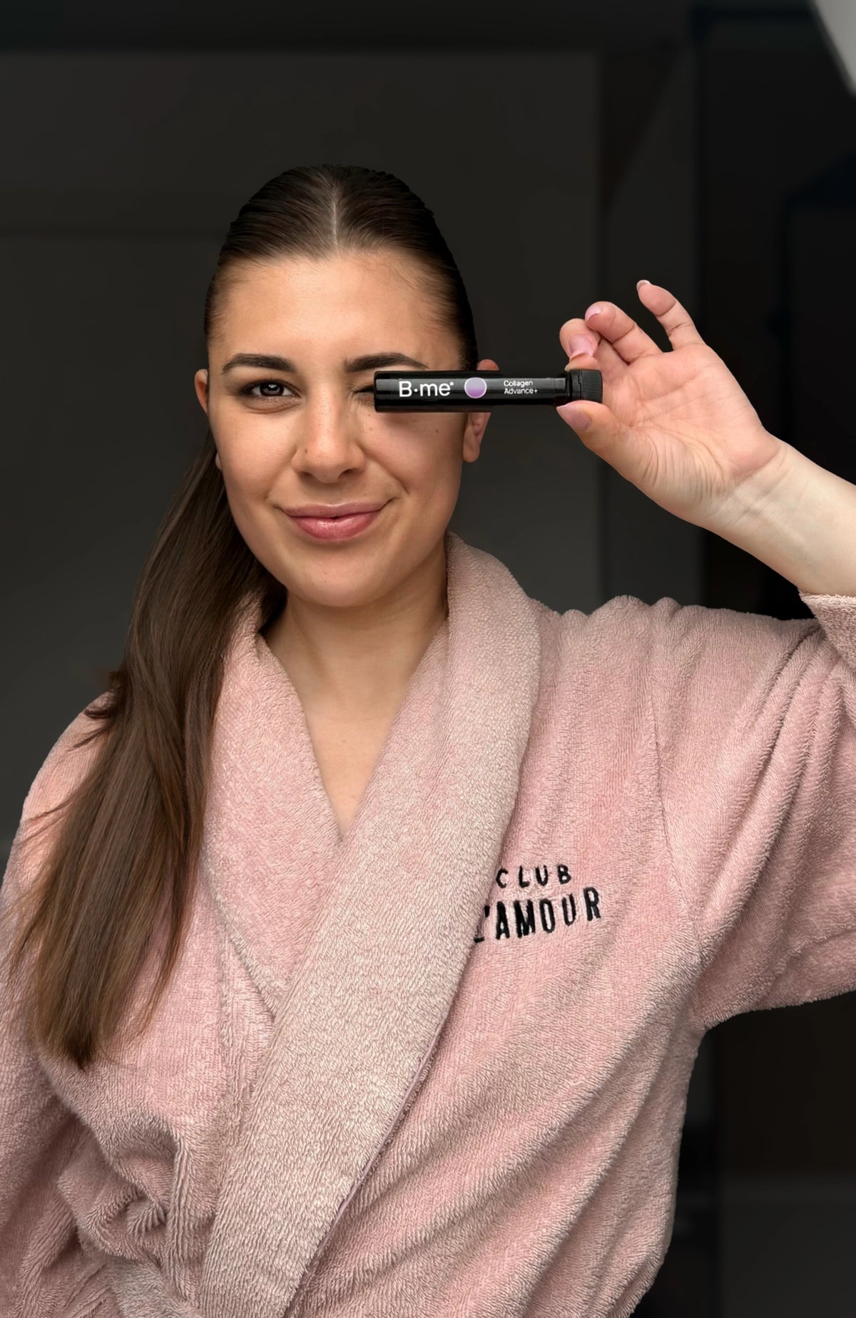 Liesa Persyn holding the B.me Clear Skin collagen shot in a pink bathrobe, sharing her glowing skin and daily skincare routine